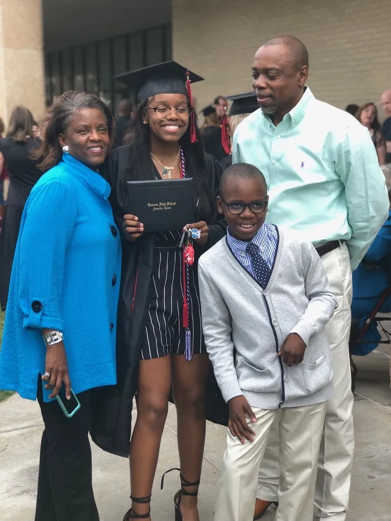 Our founder in a cap and gown holding a Tascosa High School diploma, with family on graduation day in Amarillo