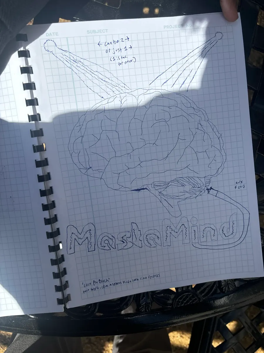 Ballpoint sketch on grid paper: a detailed brain under two spotlights, “MastaMind” in outlined lettering and an aux cord curling out of the brain, with handwritten notes